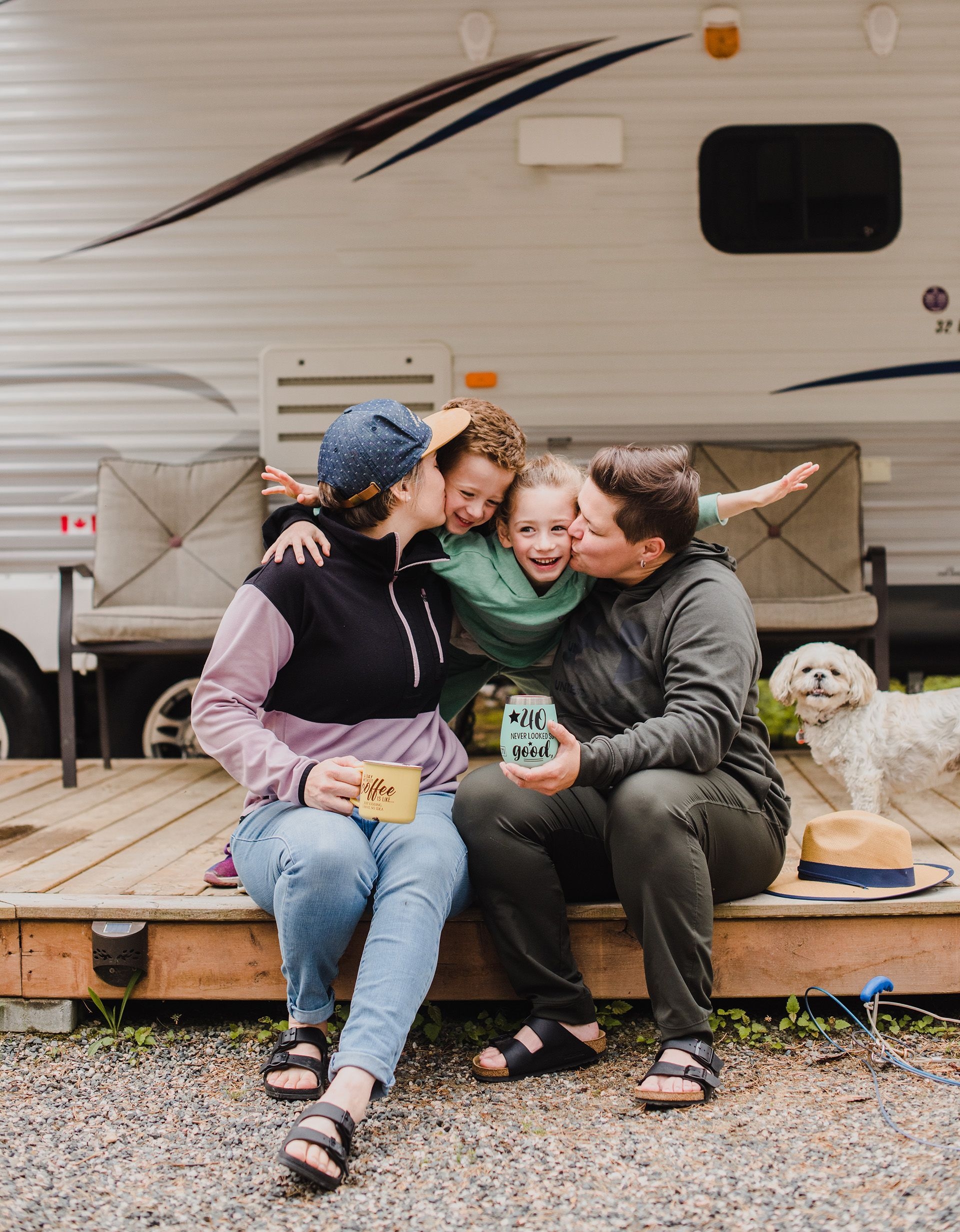 A happy family sits in front of their RV.