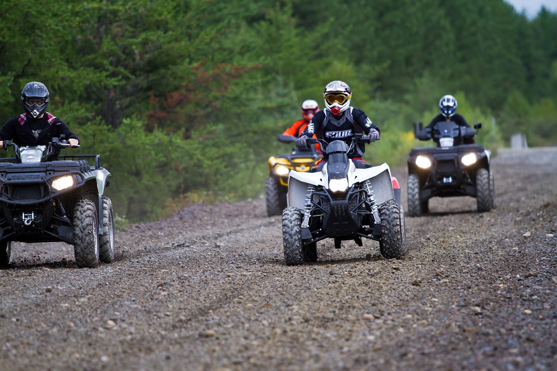 Five people ATVing on a trail.