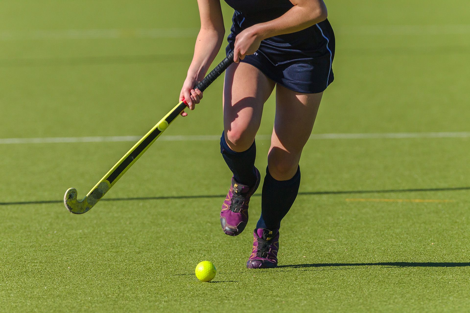 A girl playing ball hockey about to hit a ball.
