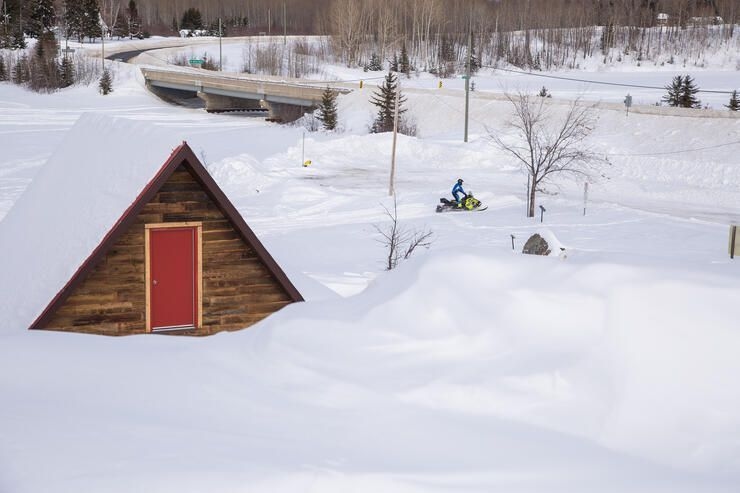 A wood cabin with a red door in the snow in Black River Matheson.