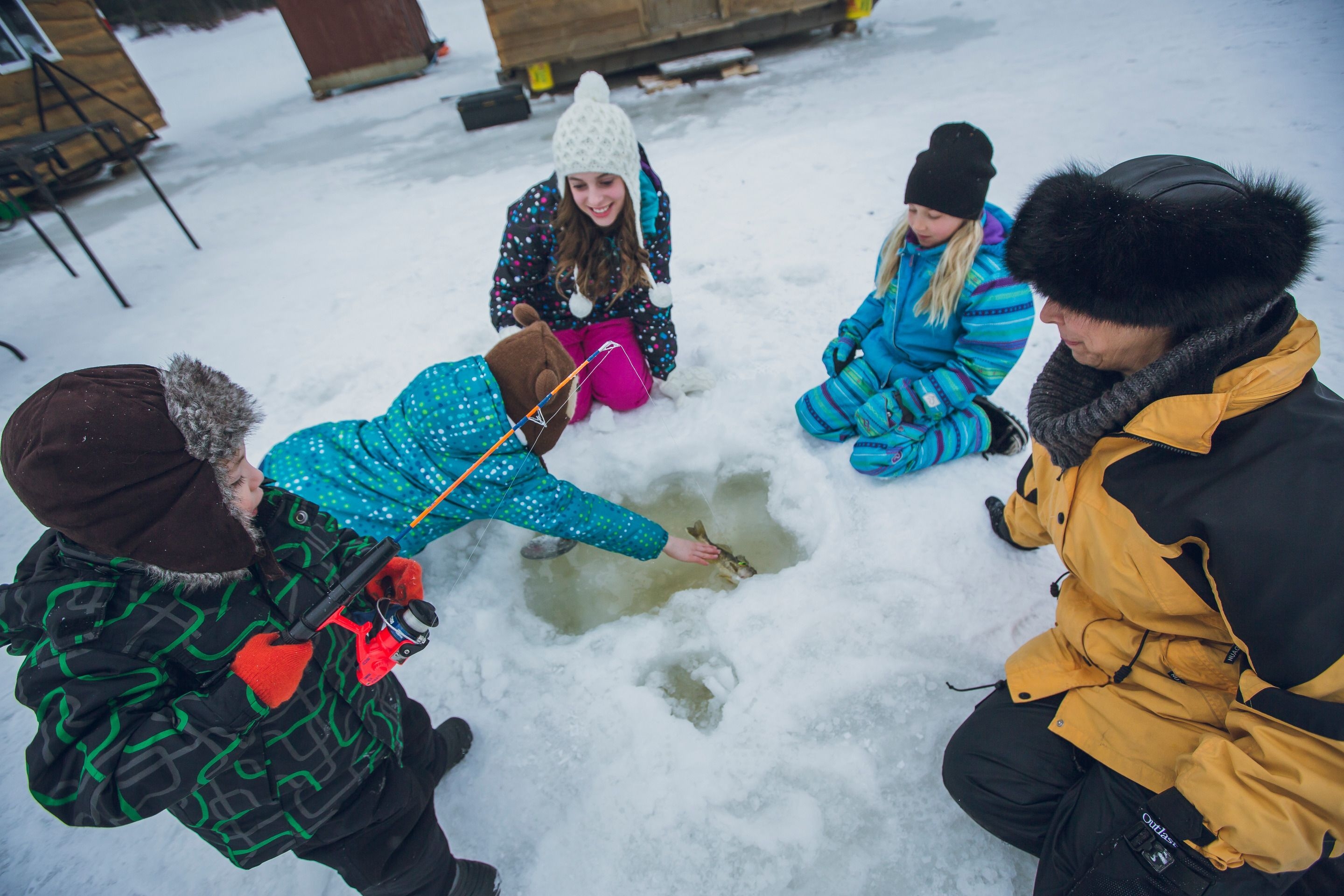 Des enfants sont attroupés autour d'un trou de pêche. 