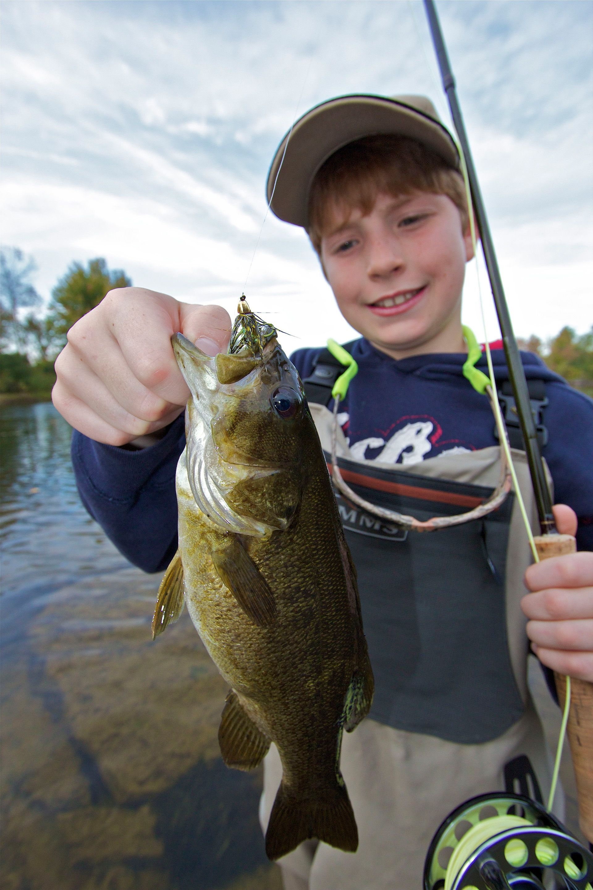 A young boy holding a fish towards the camera.