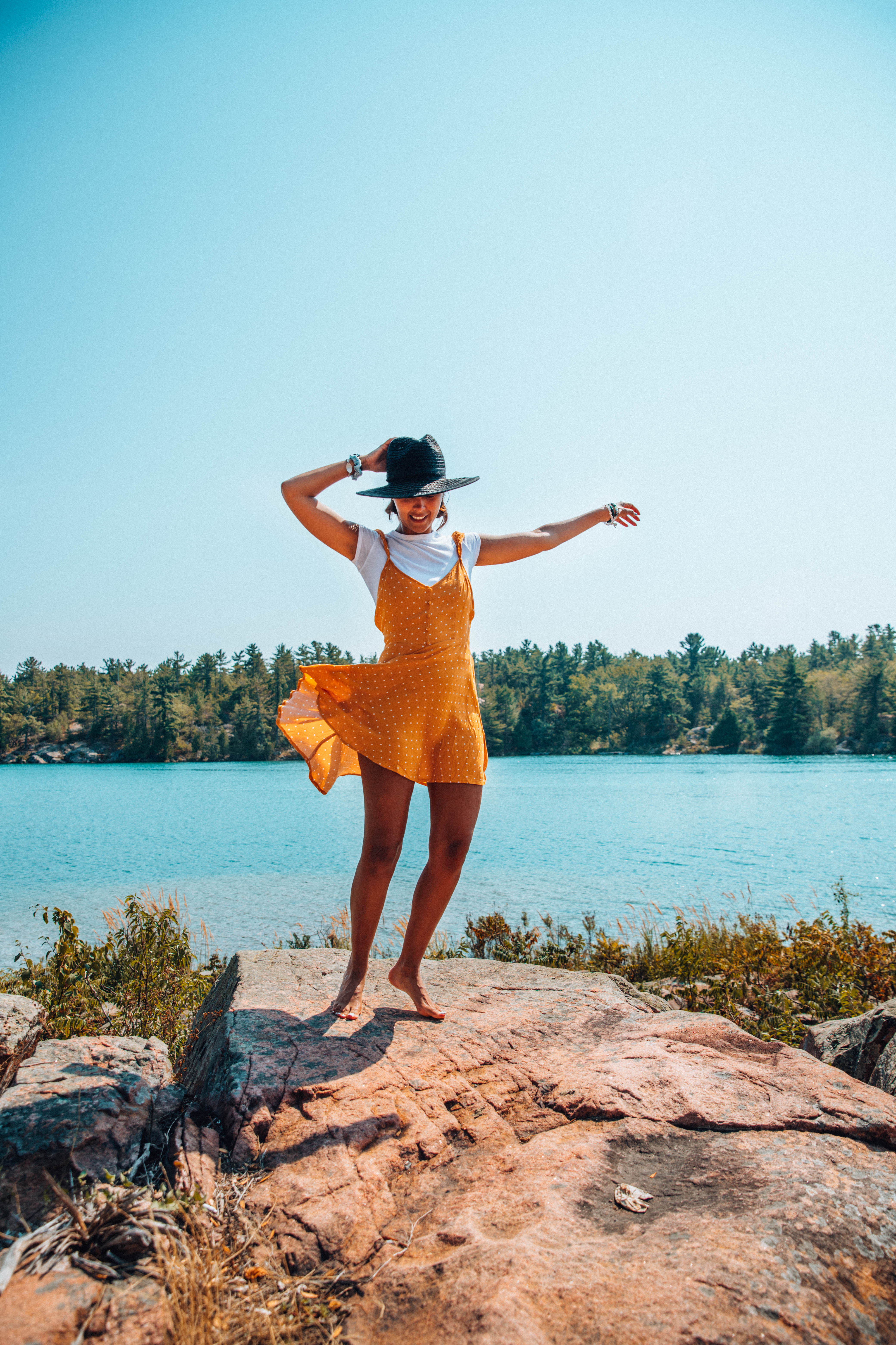 woman dancing on the rocks at killarney mountain lodge in an orange mini dress