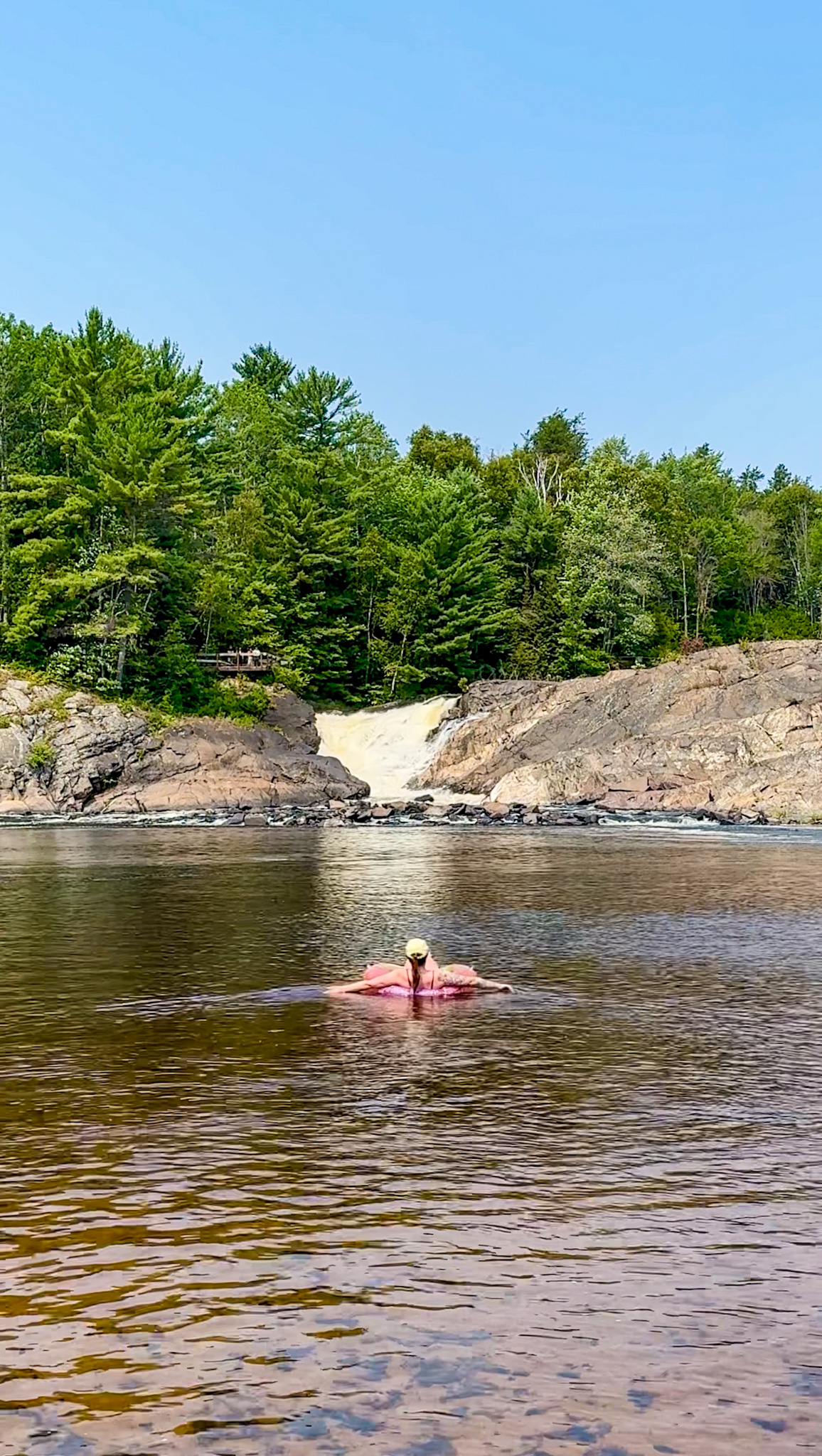 Woman on a floatie in a pool of water in front of a waterfall