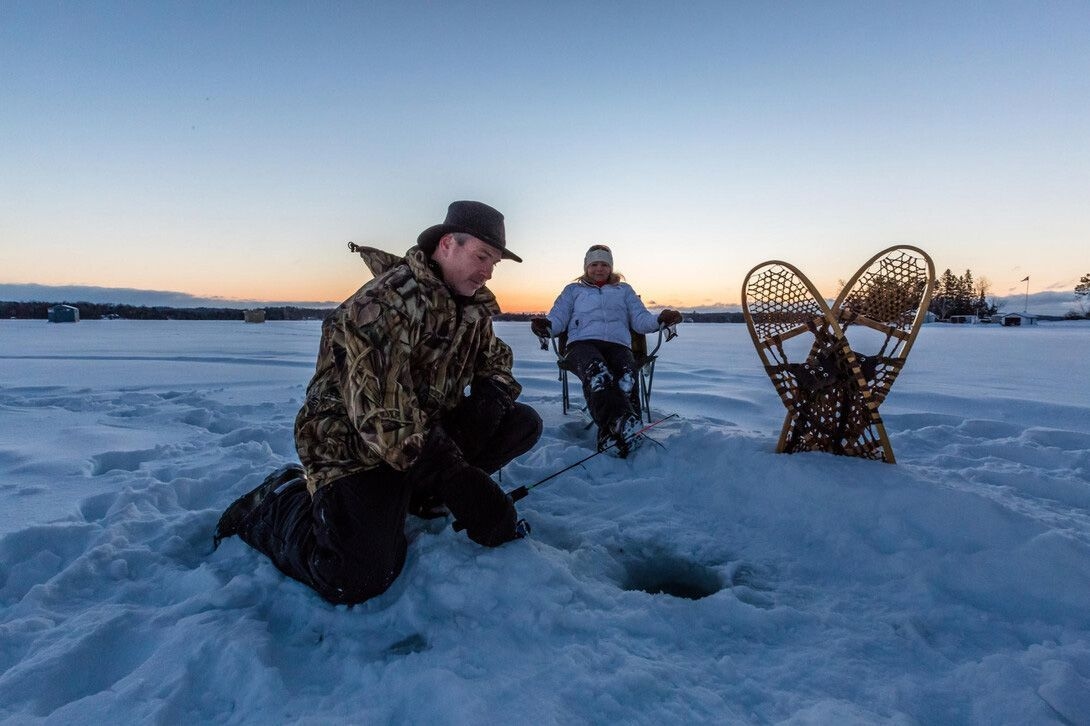 A couple ice fishes next to their snowshoes near Big Moose Camp.