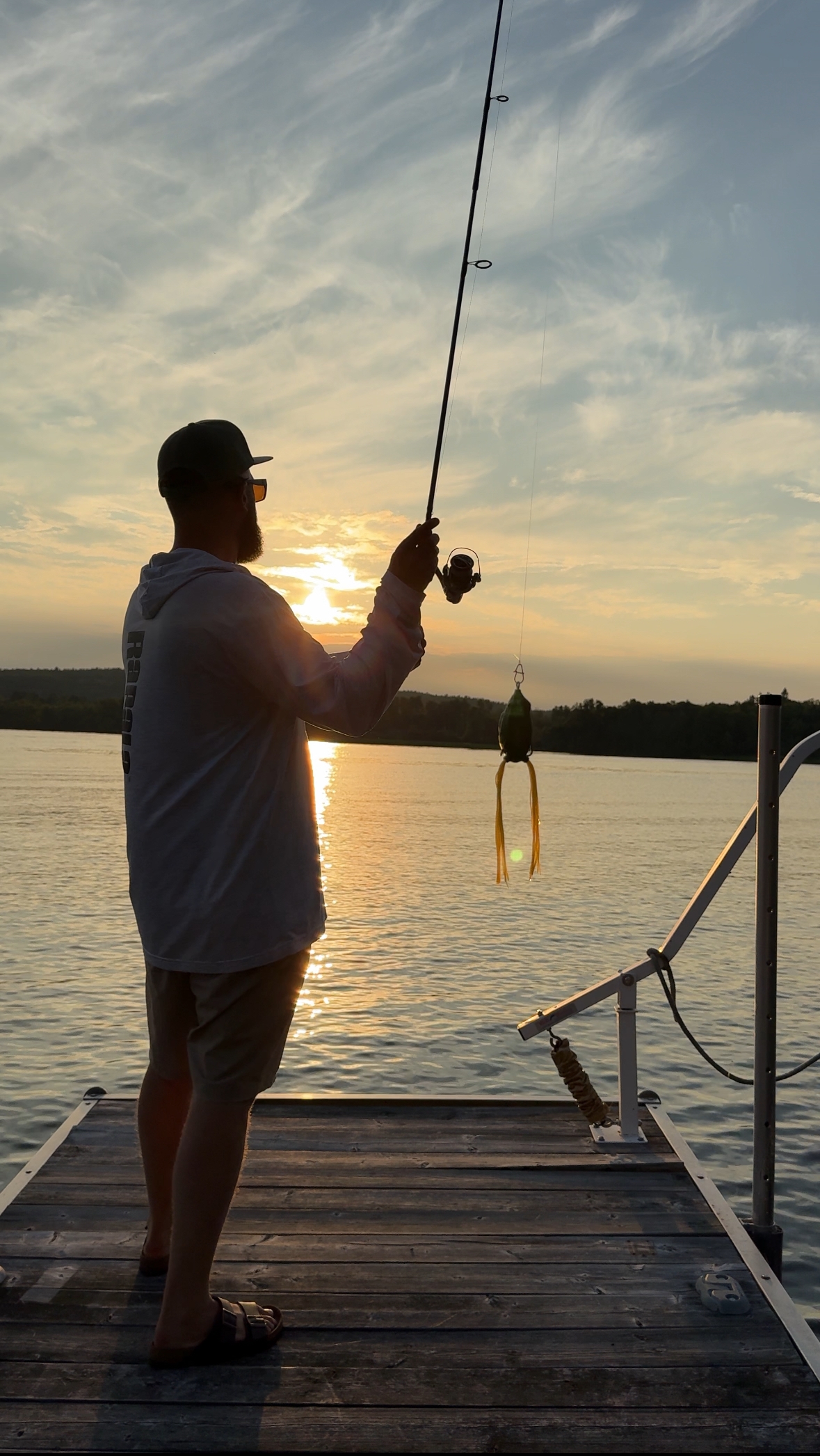 man fishing off the end of a dock at sunset