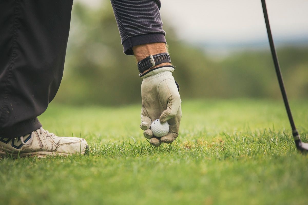 A person putting their golf ball on the tee.