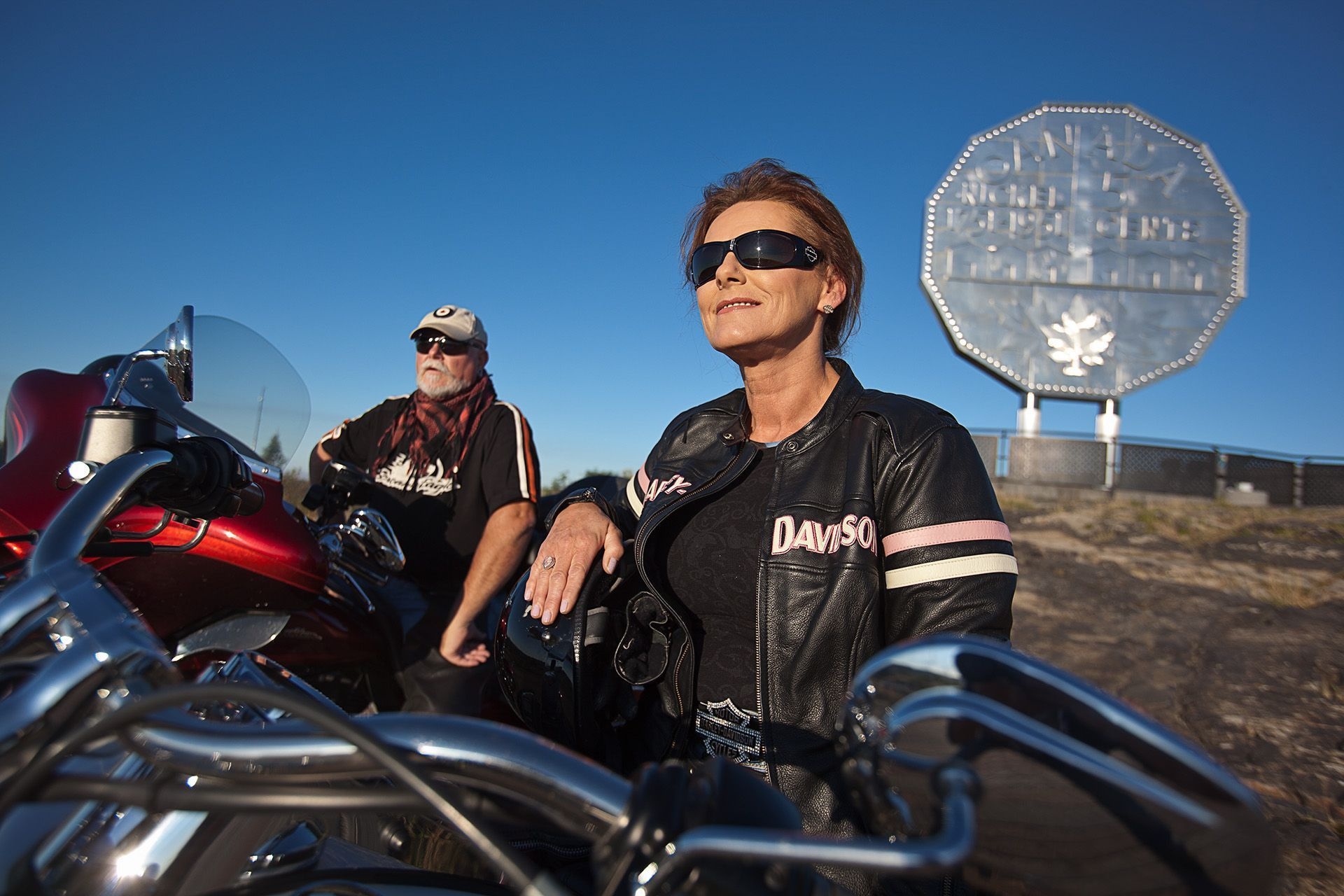 Two people on motorcycles sitting in front of the Sudbury Nickel.