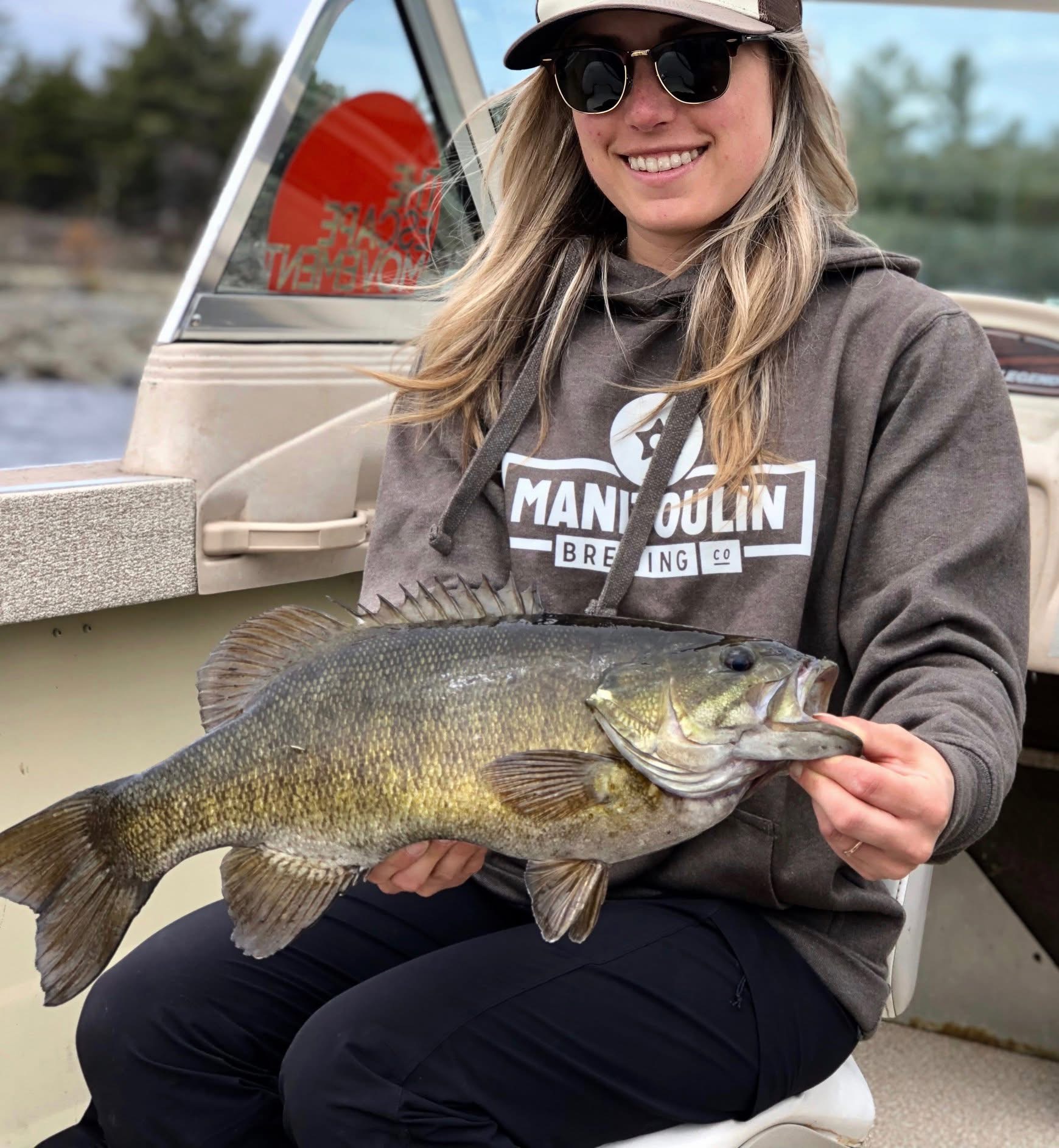 Woman in boat holding a big fish and smiling