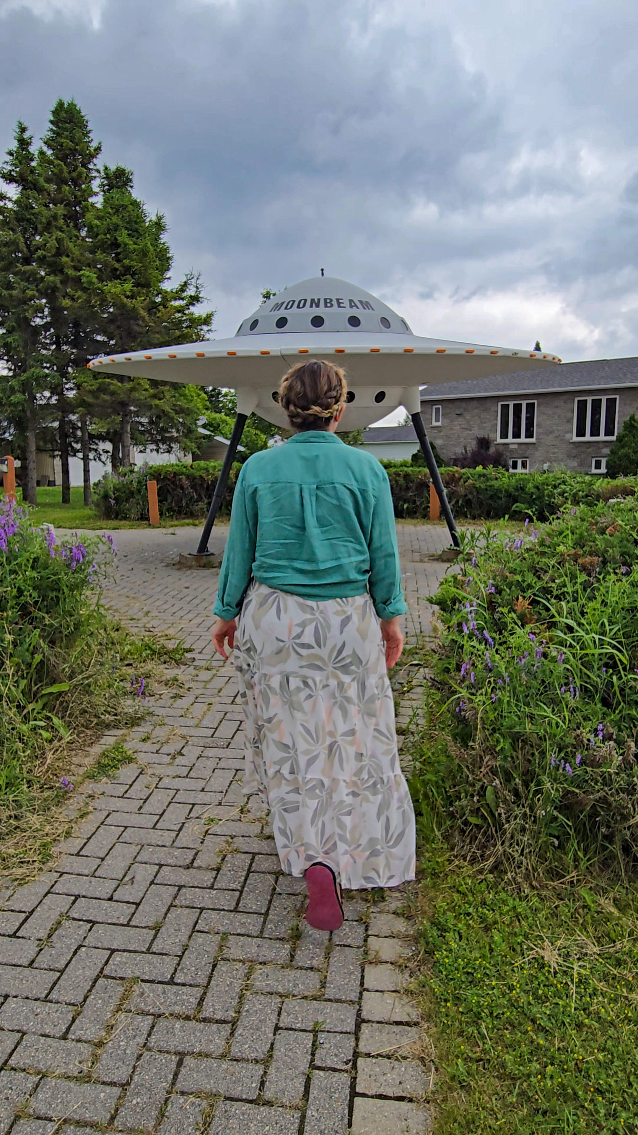 A woman in a long skirt walking toward the flying saucer roadside attraction in Moonbeam