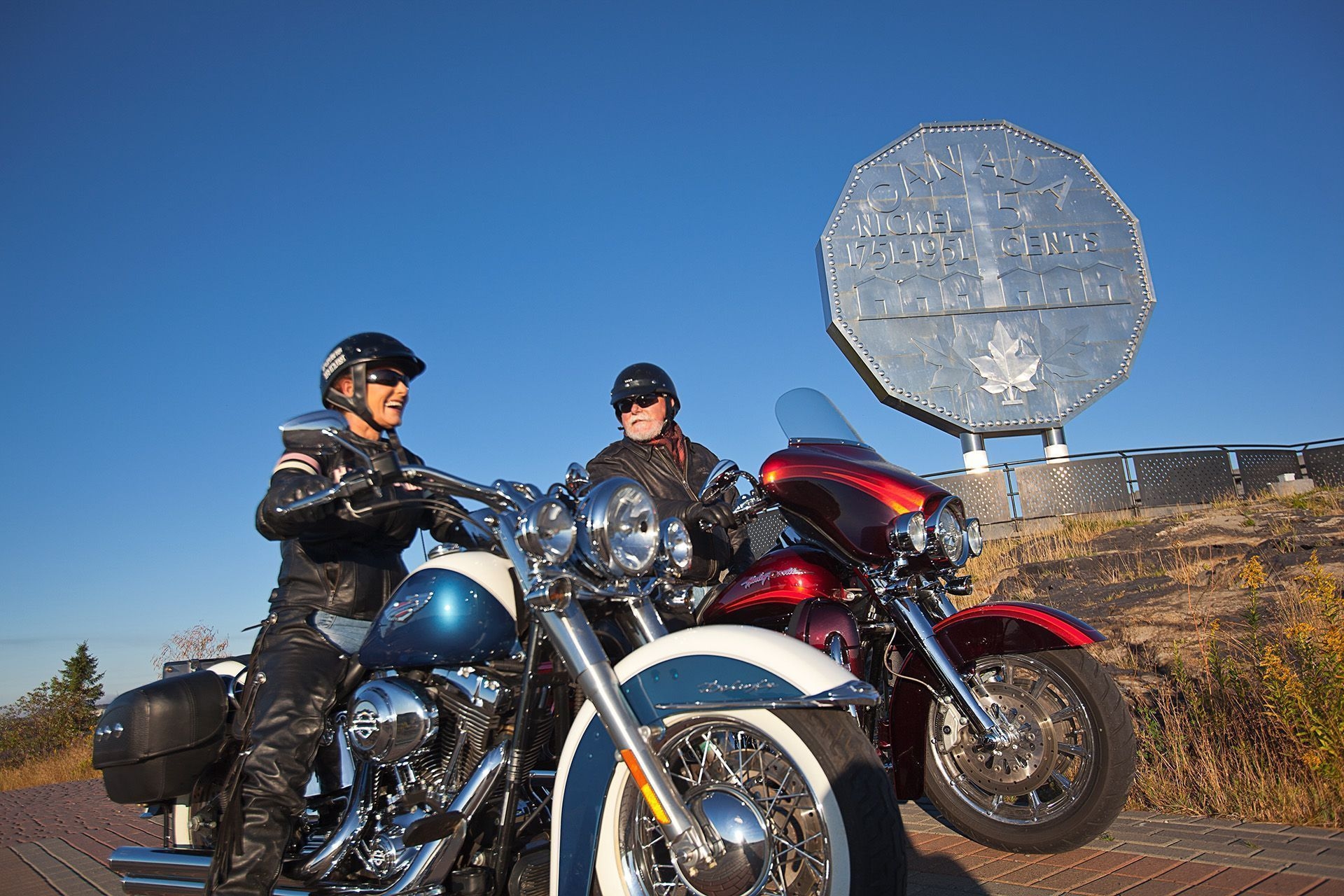 Two people on motorcycles sitting in front of the Sudbury Nickel.