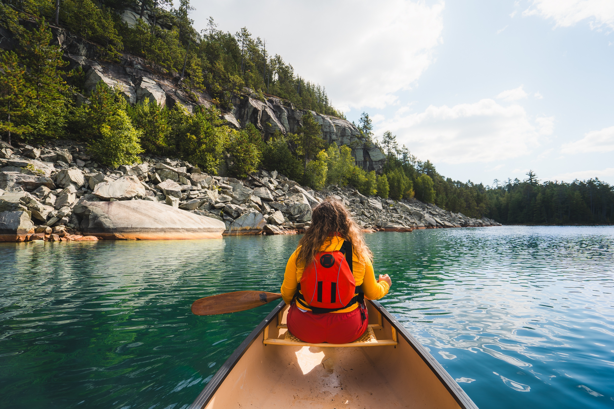 Woman paddling a canoe along the shores of Wolf lake