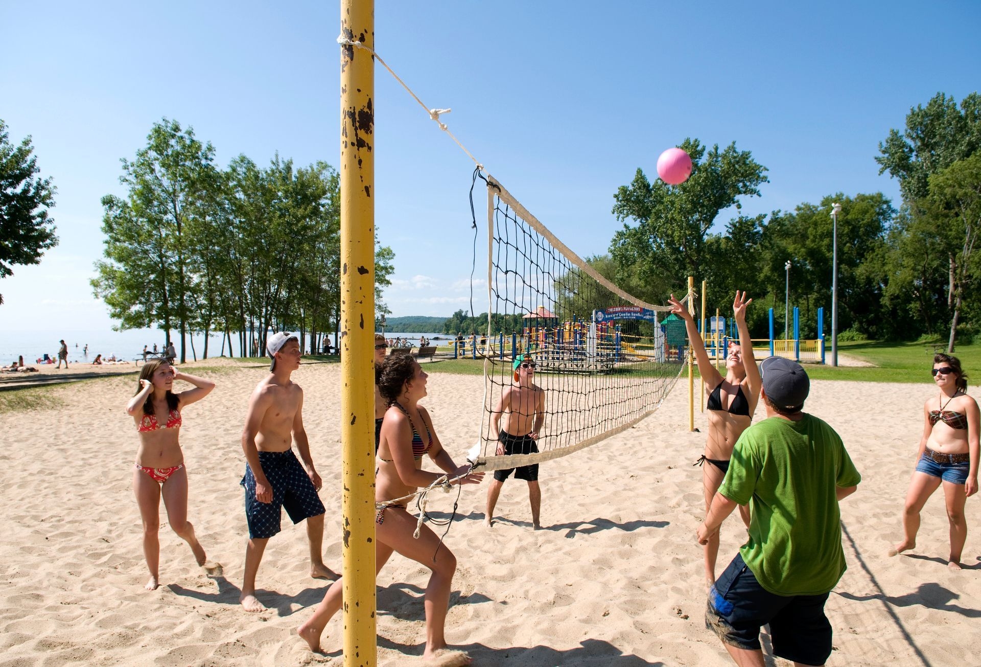 A group of people play volleyball at a beach in North Bay.
