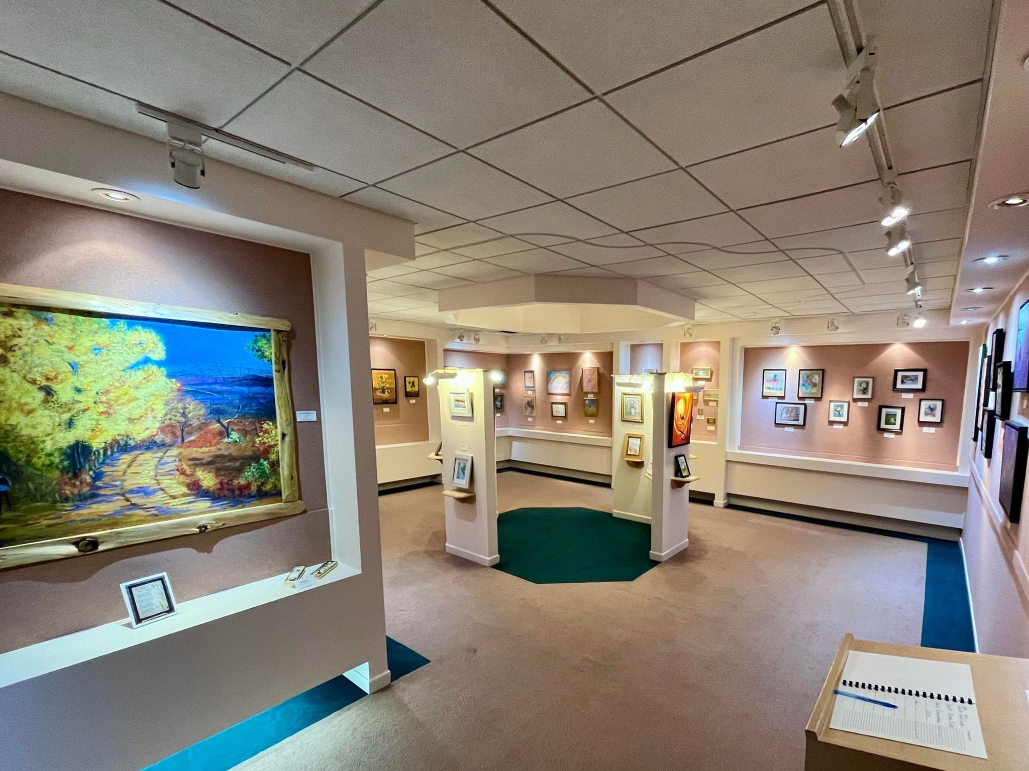 a gallery room with many framed paintings and drawings hung on the walls