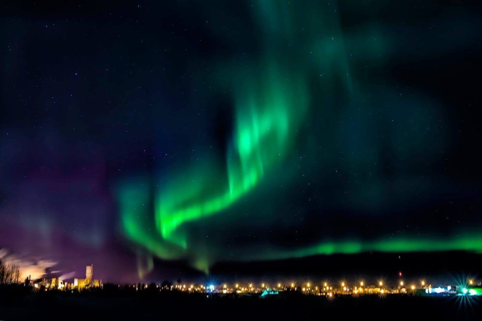 A green and pink Aurora Borealis shines above the town of Hearst.