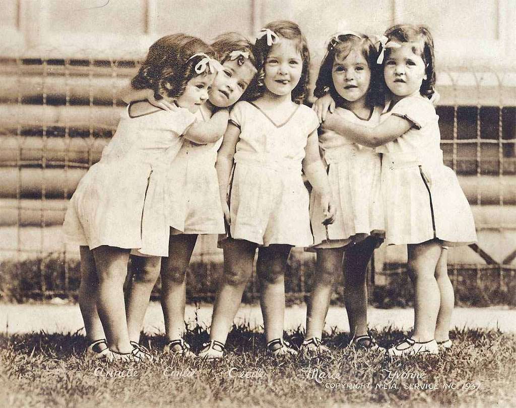 A black and white photo of the Dionna Quintuplets as children taken in 1937.