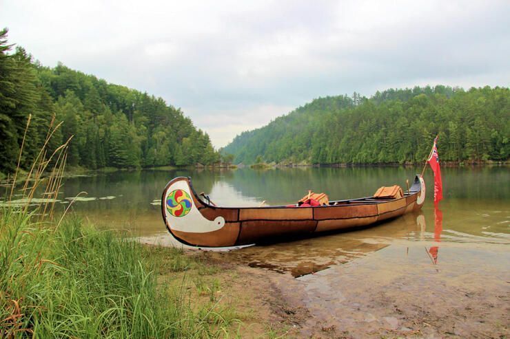 A birch bark canoe rests of the riverbank of the Mattawa River.