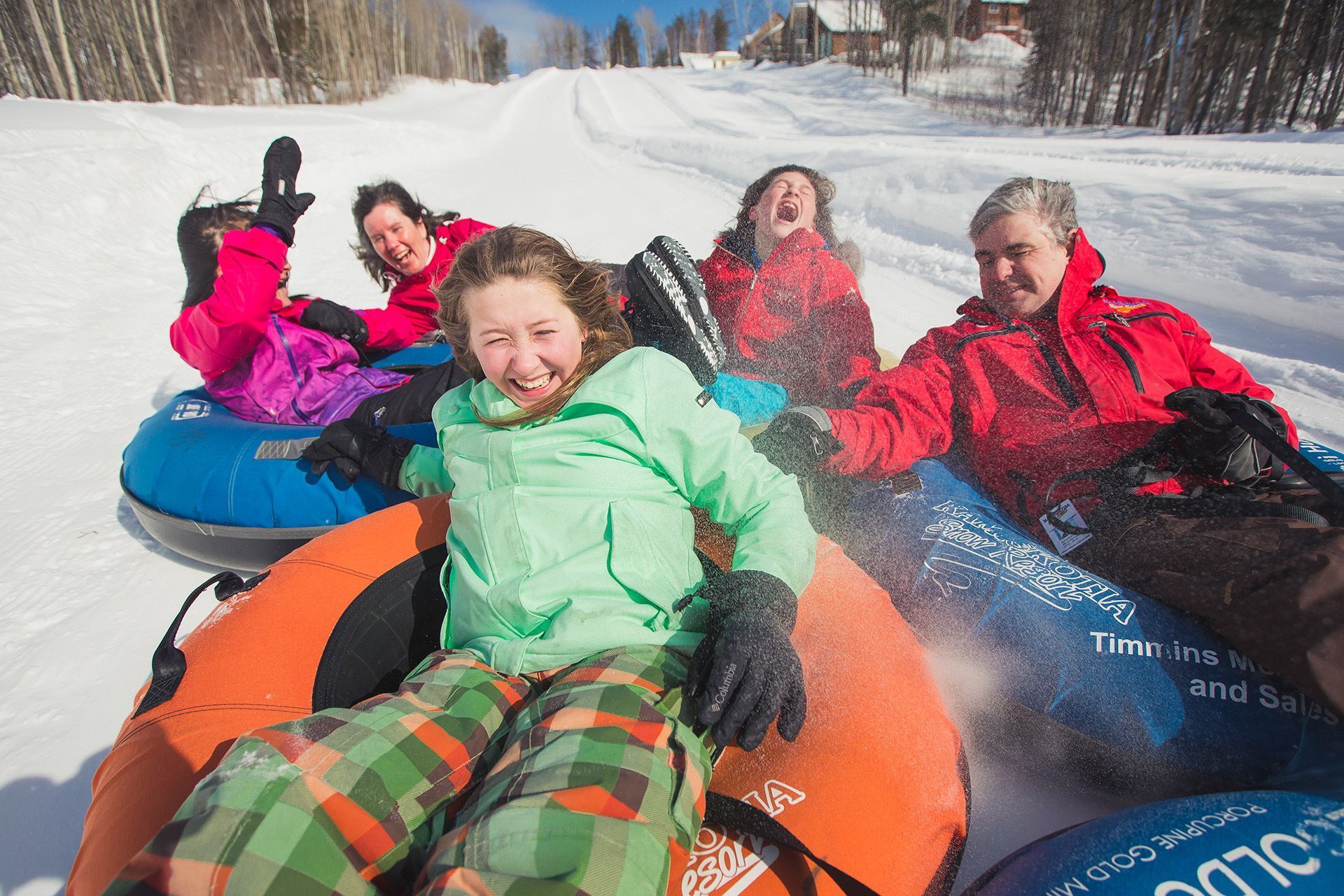 A family rides in colourful tubes down a hill.