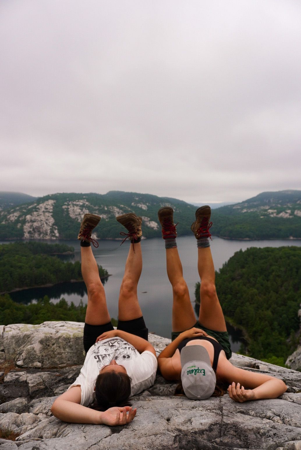 Deux filles sont couchées sur le dos, les jambes droit dans les airs. Elles sont au sommet d'une falaise rocheuse dans le parc provincial Killarney.