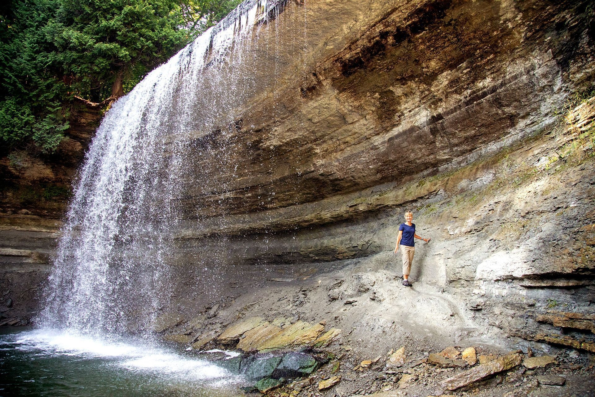 A woman stands on a rock outcrop behind the Bridal Veil Falls on Manitoulin Island.