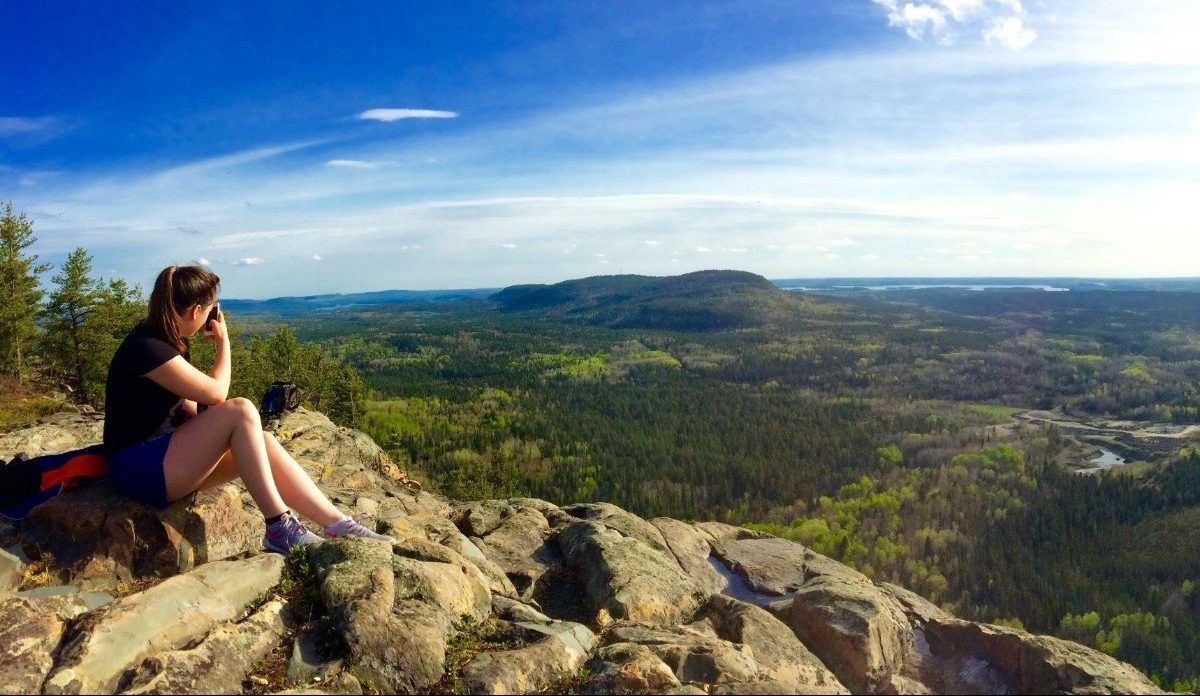 Du au du mont Chaudron, on voit les environs : de la forêt! Une femme est assise sur un flanc rocheux et admire le paysage.