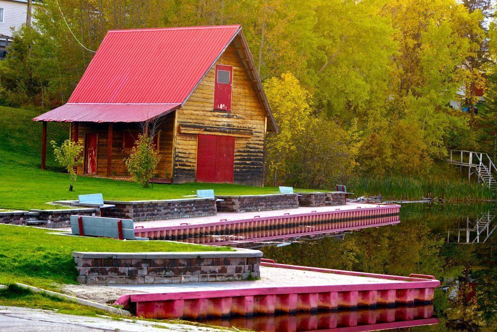 A wood cabin with a red roof by a pond in Black River Matheson.